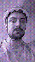 a selfie of a white person, wearing either headphones or a helmet, making an odd expression. the photo is edited to be colorized into a monochrome purple-ish color palette.
